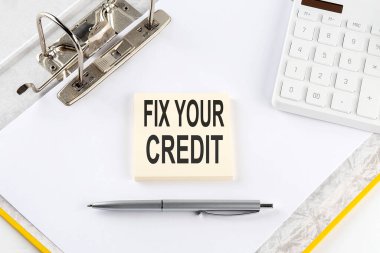 FIX YOUR CREDIT - business concept, message on the sticker on the folder background with calculator