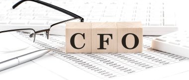 CFO written on wooden cube with keyboard , calculator, chart,glasses.Business