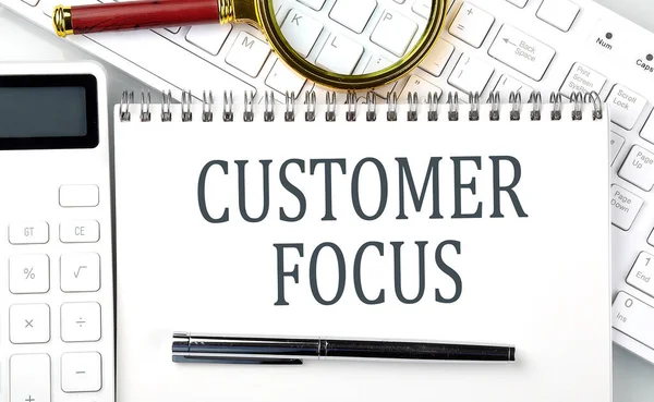 CUSTOMER FOCUS Text on the notepad with calculator and keyboard,business concept