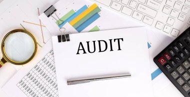 AUDIT beyaz kağıtta grafik kağıdı, klavye ve hesap makinesi ile ışık arkaplanı üzerine metni