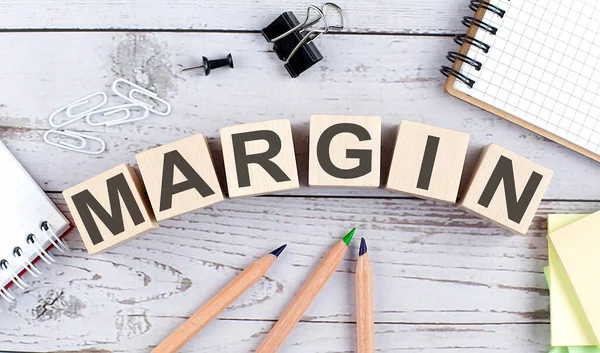 Ahşap bloktaki MARGIN metni ve ahşap arkaplanda ofis araçları
