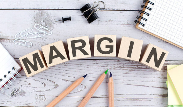 MARGIN text on wooden block with office tools on wooden background