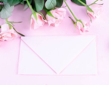 Pembe güller ve pembe zarf pembe arka planda, kopyalama alanı