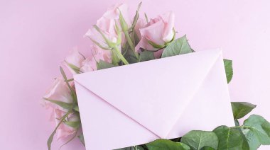 Pembe güller ve pembe zarf pembe arka planda, kopyalama alanı