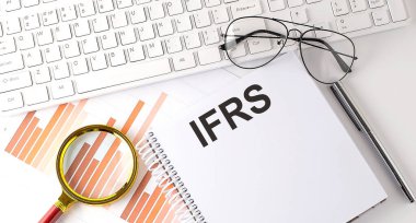 IFRS klavye, grafik ve gözlük ile deftere yazılmış metin