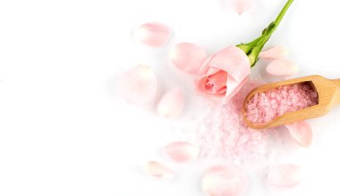 Gül yaprakları ve ahşap kaşık pembe bir tuz üzerinde, kopyalama alanı