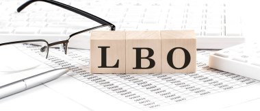 LBO written on wooden cube with keyboard , calculator, chart,glasses.Business clipart