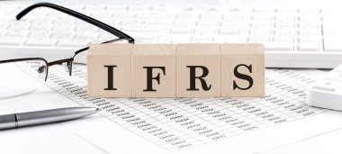 IFRS, klavye, hesap makinesi, çizelge ve gözlüklerle tahta küpte yazılı.