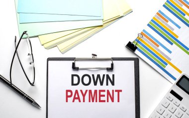 Kağıtların üzerinde tablo, renk kağıdı ve hesap makinesiyle DOWN PAYMENT metni