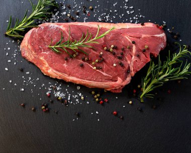 Baharatlı çiğ biftek ve koyu arkaplanda biberiye. Kopyalama alanı olan üst görünüm.