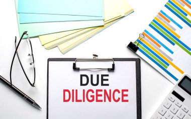 Dosya, renk kağıdı ve hesap makinesiyle kağıt üzerinde DUE DILIGENCE metni