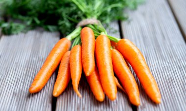 Tahta masada yeşil tepeli taze organik havuçlar, yakın plan.