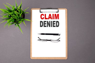 Gri arkaplandaki kahverengi panoya CLAIM DENIED 'i yaz. İş konsepti
