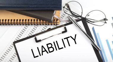 Not defterleri, malzemeler, analiz çizelgesi ile ofis masasında beyaz arkaplanda LIABILITY metni.