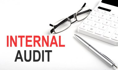 Interternal AUDIT kavramı. Beyaz arkaplanda hesap makinesi, kalem ve gözlük