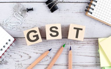 Ahşap blokta GST metin ve ahşap arka planda ofis araçları