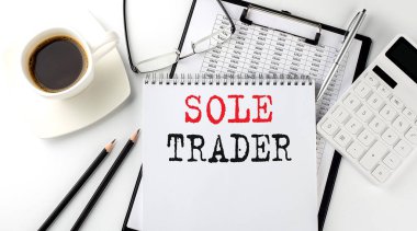SOLE TRADER kağıt üzerinde metin hesap makinesi, not defteri, kahve, grafik ile kalem