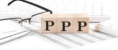 Klavye, hesap makinesi, çizelge, gözlük ile ahşap küp üzerine PPP yazıldı. İş
