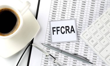 FFCRA metin üzerinde yapışkan bir tablo üzerinde kahve, kalem ve hesap makinesi ile