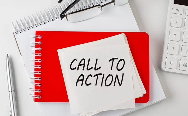 CALL TO ACTION word on the sticker on notepad with pen and calculator