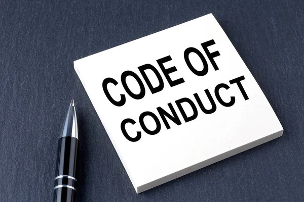 CODE OF CONDUCT text on the sticker with pen on black background