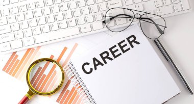 Klavye, çizelge ve gözlük ile deftere yazılmış CAREER metni