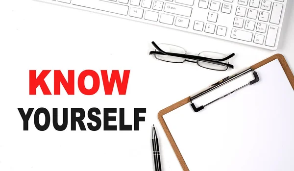 KNOW YOURSELF text written on white background with keyboard, paper sheet and pen