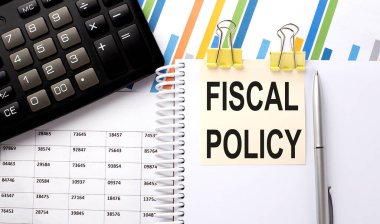 FISCAL POLICY metin, hesap makinesi ile bir çıkartma üzerine yazılmış, grafik arkaplanda kalem.