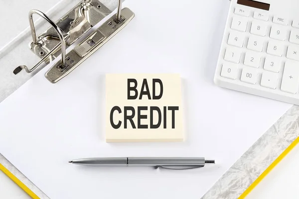BAD CREDIT - business concept, message on sticker on folder background with calculator