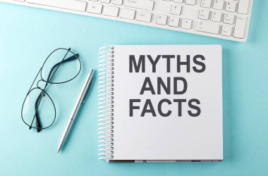 Mavi arkaplanda klavye, defter, kalem ve gözlük, metin MYTHS ve Gerçekler