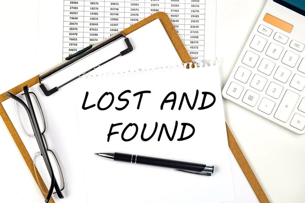 Text LOST AND FOUND on the white paper on a clipboard with chart and calculator