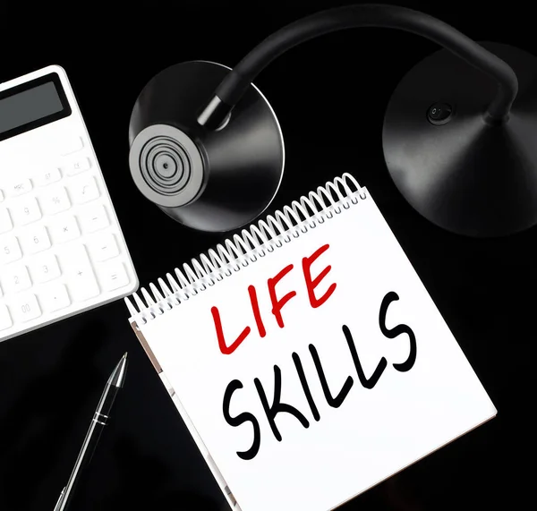 Siyah arkaplan üzerinde LIFE SKILLS metin bir kalem, hesap makinesi ve masa lambası ile açılan kağıt defter.