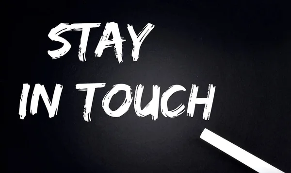 STAY IN TOUCH Text on Black Chalkboard with piece of chalk