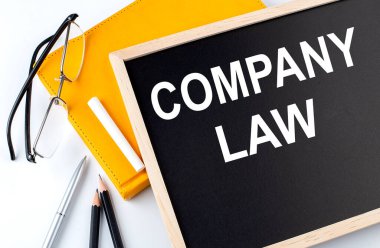 Not defteri ve kalemle birlikte bir karatahtadaki COMPANY Yasa metni