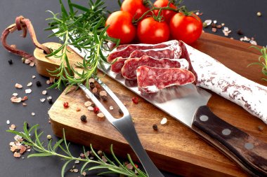 Geleneksel sosis bıçakla, çatalla, biberiyeyle ve baharatlarla dilimlenmiş tahta kesme tahtasıyla. .