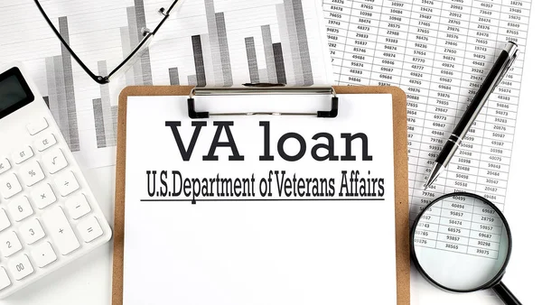 Paper with VA loan on a chart with calculator,pen and magnifier
