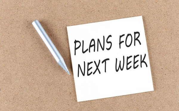 PLANS FOR NEXT WEEK text on sticky note on a cork board with pencil