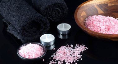 Siyah havlular, beyaz orkideler ve siyah arka planda pembe deniz tuzu olan siyah spa seti. Spa konsepti