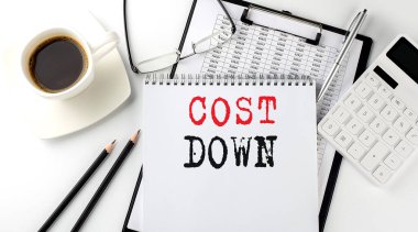 Kağıt üzerinde bir hesap makinesi, not defteri, kahve, grafikli kalem ile COST Down metni