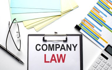 Çizelge, renk kağıdı ve hesap makinesi olan bir kağıt üzerinde COMPANY Yasa metni