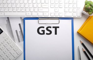 Klavye, grafik, hesap makinesi ve not defteri olan bir kağıda GST yazıldı