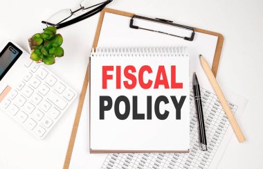Kağıt kağıdı, not defteri, çizelgesi ve hesap makinesi olan bir ofis masası. Üst görünüm metni FISCAL POLİSİ