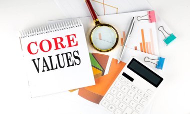 Beyaz arkaplanda diyagramı, grafiği ve hesap makinesi olan beyaz not defteri metni CORE VALUES