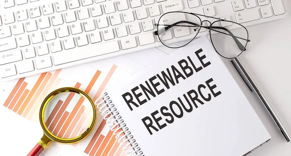 RENEWABLE RESOURCE text written on notebook with keyboard, chart,and glasses