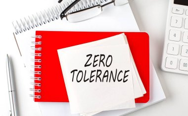 Sıfır TOLERANCE sözcüğü not defterindeki etiket üzerinde kalem ve hesap makinesiyle