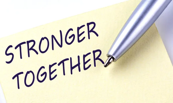Sticky Note Message STRONGER TOGETHER with pen on white background