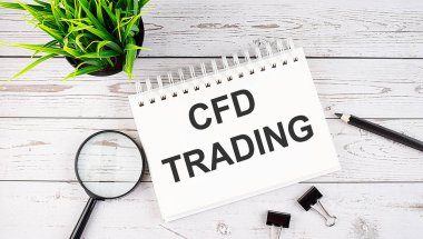 CFD TRADING text concept write on notebook with office tools on wooden background clipart