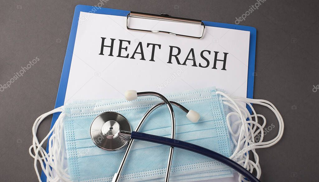 Folder with paper text HEAT RASH , on a table with a stethoscope and medical masks, medical