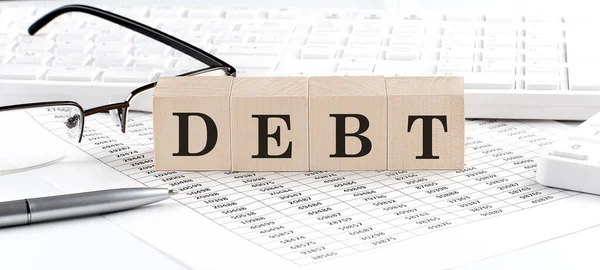 用键盘 计算器 眼镜写在木制立方体上的Debt — 图库照片