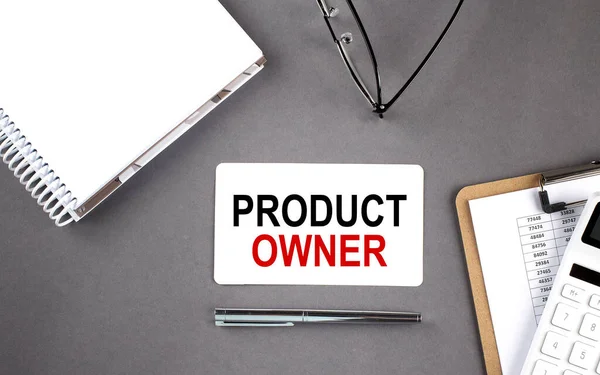 PRODUCT OWNER. Text written on card with notebook and clipboard, grey background
